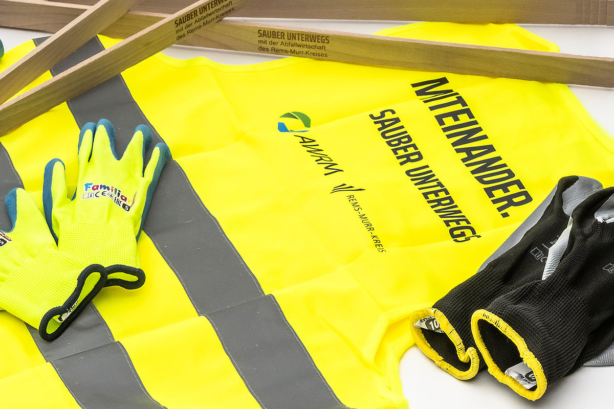 Ausrüstung für die Kreisputzete: Warnweste, Handschuhe, Müllsäcke und Holzgreifzangen mit dem Aufdruck ‚Sauber unterwegs‘.