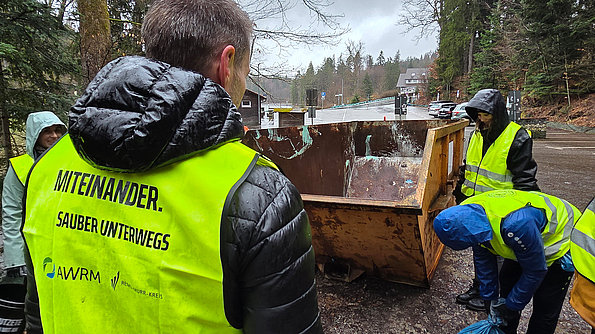 Müllcontainer und Personen mit Warnweste der AWRM