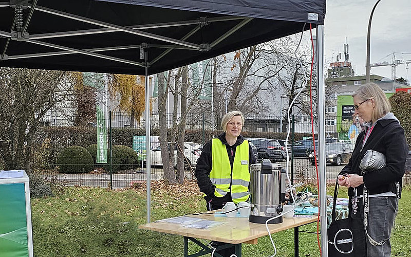Mitarbeiterin und Bürgerin unterhalten sich an einem Infostand der AWRM