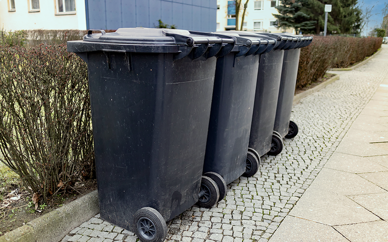 Vier schwarze Restmülltonnen in einer Reihe