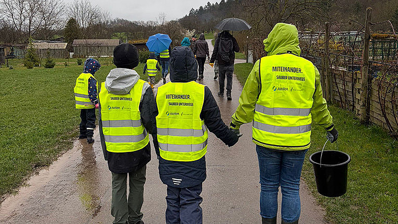 Menschen mit Warnweste AWRM von hinten beim Müllsammeln