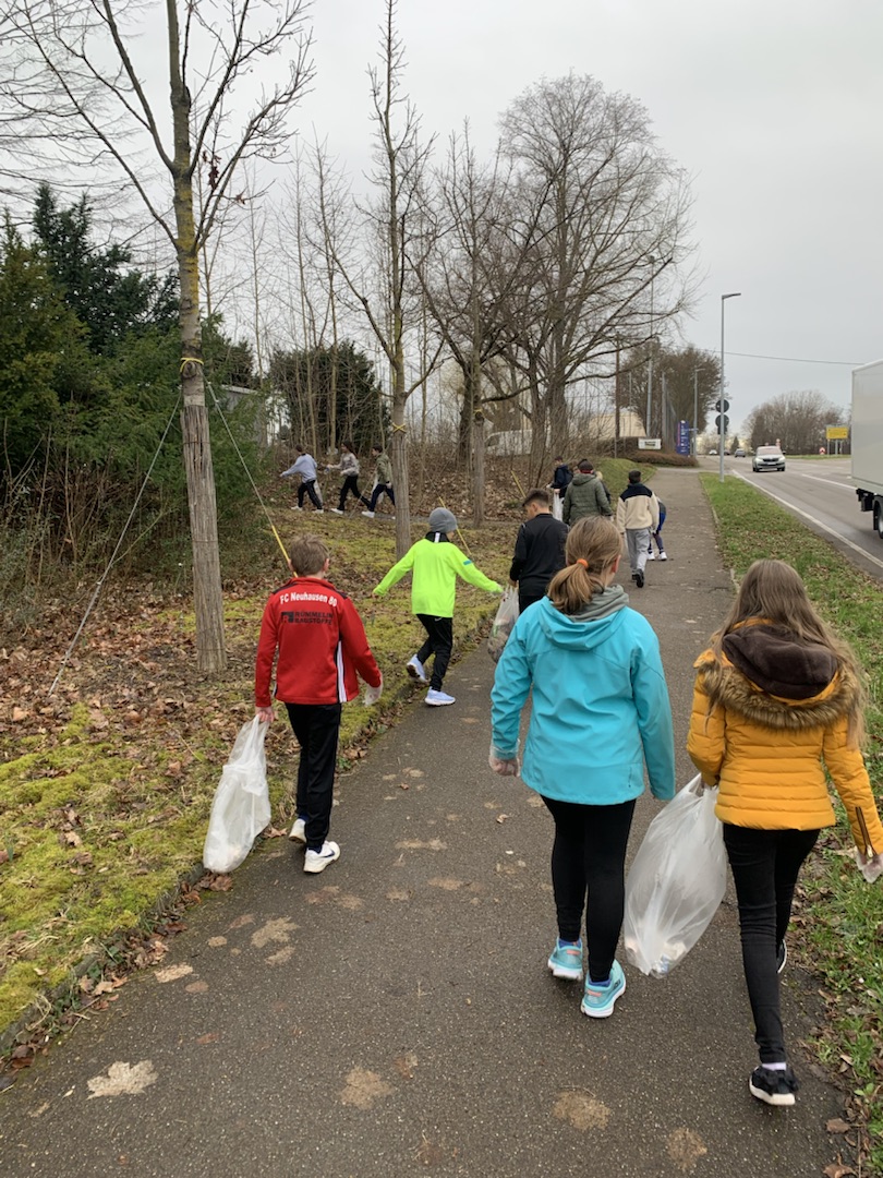 Kinder und Jugendliche sammeln bei der Kreisputzete in Fellbach Müll am Straßenrand und im Gebüsch.